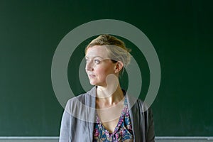 Young female teacher looking pensively aside in class