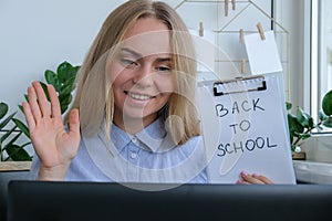 Young female teacher sitting at desk and using laptop at home. e Education Back to school. Student learning online class