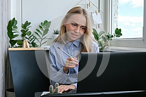 Young female teacher sitting at desk and using laptop at home. e Education Back to school. Student learning online class