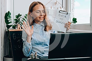 Young female teacher sitting at desk and using laptop at home. e Education Back to school. Student learning online class