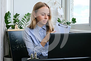 Young female teacher sitting at desk and using laptop at home. e Education Back to school. Student learning online class
