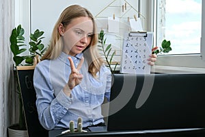 Young female teacher sitting at desk and using laptop at home. e Education Back to school. Student learning online class