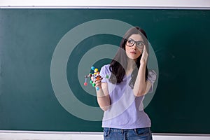 The young female teacher student in front of green board