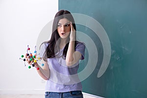 The young female teacher student in front of green board