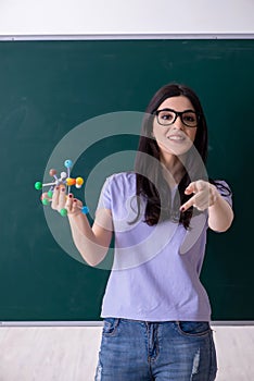 Young female teacher student in front of green board