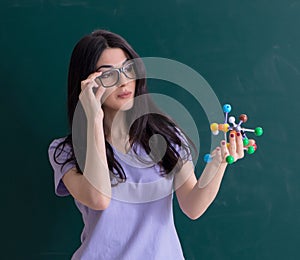 Young female teacher student in front of green board