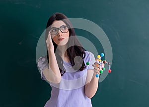 Young female teacher student in front of green board