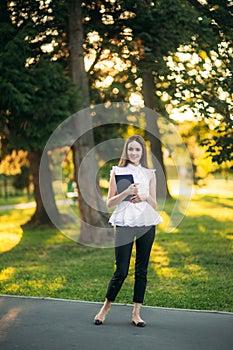 Young female teacher with tablet outside. Modern teacher in the park. Woman wears glasses