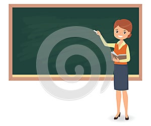 Young female teacher is writing chalk on a school blackboard