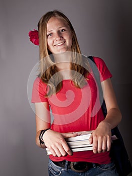 Young female teenage student carrying books