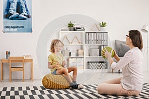 Young female therapist playing with a happy orphaned boy during