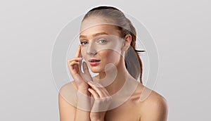 Young Female Touching Face Caring For Skin Over Gray Background