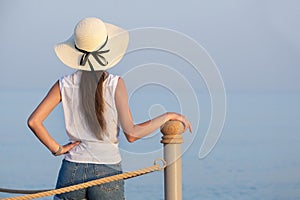 Young female tourist in casual clothes enjoying warm sunny day on sea shore. Summer vacations and travelling concept