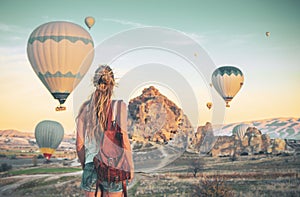 Young female tourist with colorful hot air balloon flying over Cappadocia landscape