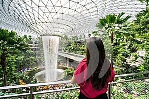 Young female tourist looking at the indoor waterfall in Changi Airport