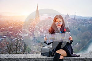 Young female tourist with map looking for a way to Beautiful view point near old town in Bern, Switzerland
