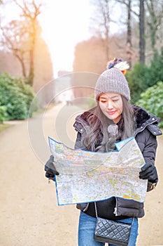 Young female tourist with map looking for a way to Sans Souci palace in Potsdam, Berlin, Germany, Europe