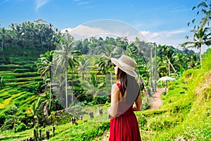 Young female tourist in red dress looking at the beautiful tegalalang rice terrace in Bali,