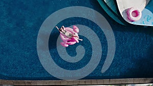 Young female tourist sunbathing in beach club, swim inflatable pink flaming