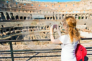 Young female tourist takes a picture inside the Coliseum in Rome