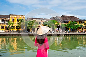 Young female tourist in Vietnamese traditional dress walking at Hoi An Ancient town