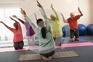 Young female trainer assisting senior people in fitness studio