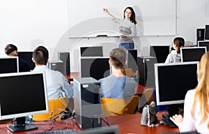 Young female trainer giving presentation to adult audience in computer class
