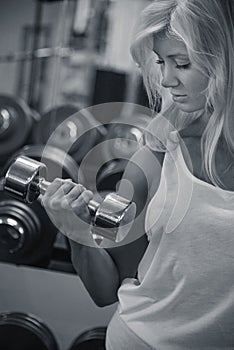 Young female training biceps in gym