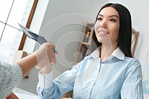 Young female travel agent consultant in tour agency with a customer passports and tickets close-up