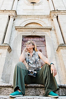 Young female traveler sitting on church steps in old town in Tuscany