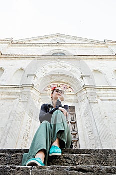 Young female traveler sitting on church steps in old town in Tuscany