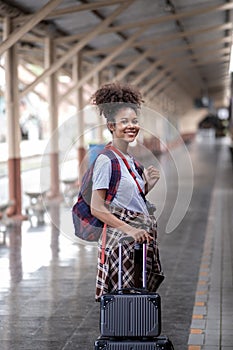 Young female traveler walking standing with a suitcase at train station. woman traveler tourist walking standing smiling