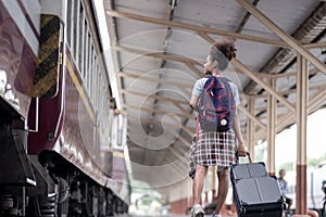 Young female traveler walking standing with a suitcase at train station. woman traveler tourist walking standing smiling