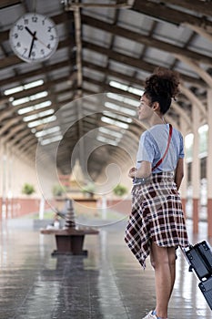 Young female traveler walking standing with a suitcase at train station. woman traveler tourist walking standing smiling