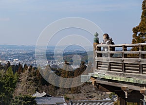 Young female traveller looking at city and landscape while travelling wearing winter white jacket.