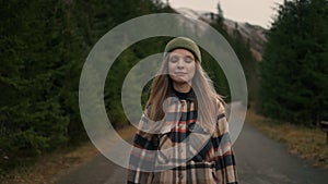 Young female traveller walking in middle of epic empty road in mountains, surrounded by nature