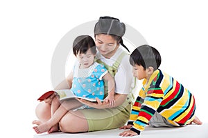 Young female with two little asian children reading a book