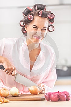 Young female with an unhappy face expression cuts onion with a knife