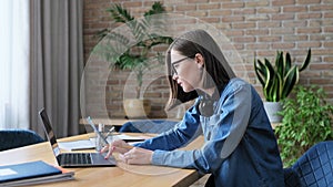 Young female university student studying at home, using laptop