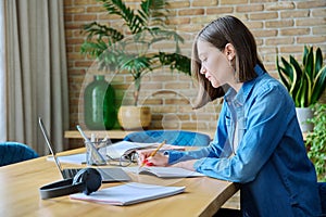 Young female university student studying at home, using laptop