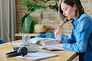 Young female university student studying at home, using laptop