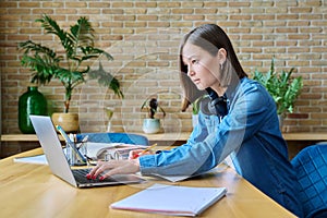 Young female university student studying at home, using laptop