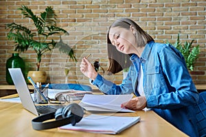 Young female university student studying at home, using laptop