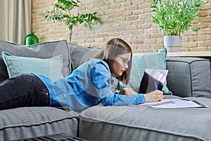 Young female university student studying at home, using laptop computer