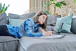 Young female university student studying at home, using laptop computer