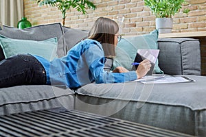 Young female university student studying at home, using laptop computer