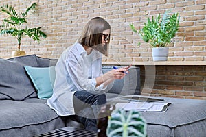 Young female university student studying at home, using smartphone