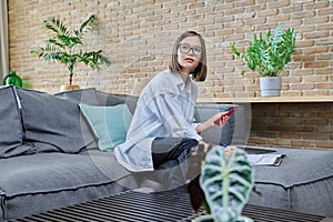 Young female university student studying at home, using smartphone