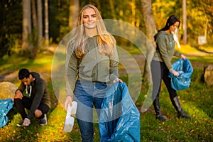 Young female volunteer holding garbage bag at park