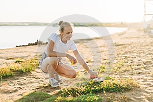 Young female volunteer satisfied with picking up trash, a plastic bottles and coffee cups, clean up beach with a sea